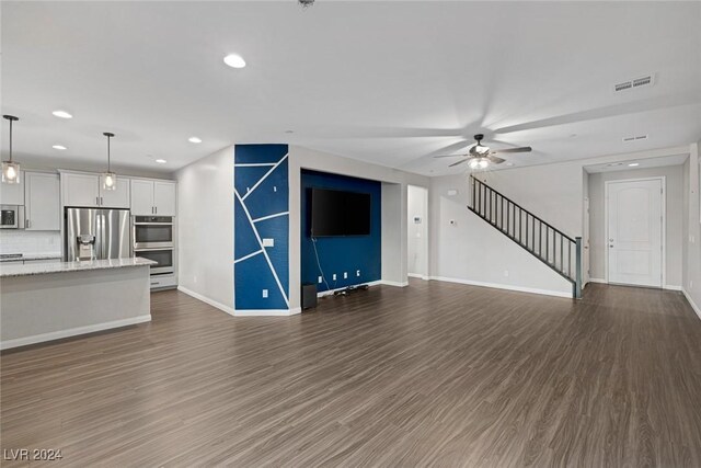 unfurnished living room featuring ceiling fan and dark wood-type flooring