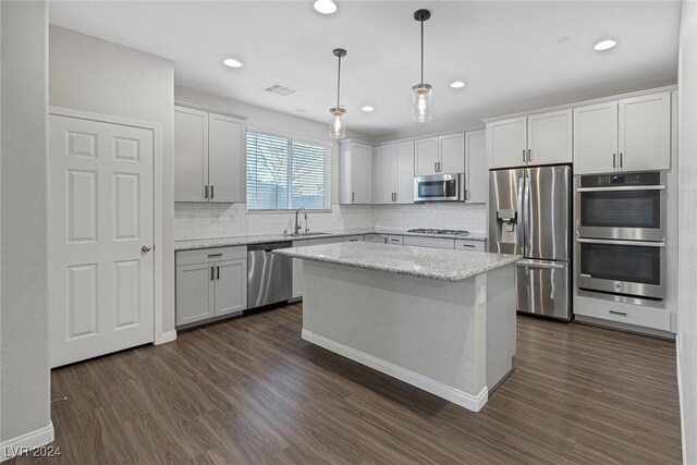 kitchen with white cabinetry, appliances with stainless steel finishes, dark hardwood / wood-style floors, a kitchen island, and pendant lighting