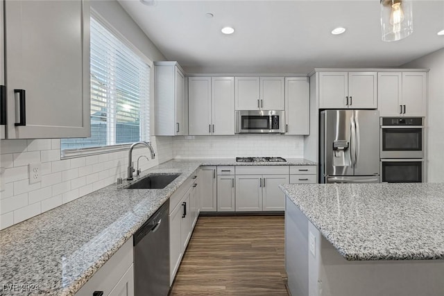 kitchen featuring light stone countertops, white cabinets, stainless steel appliances, tasteful backsplash, and sink