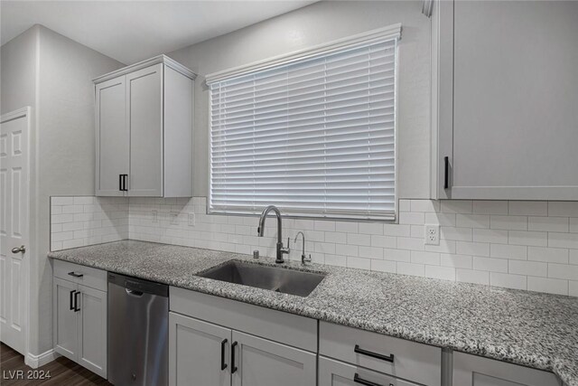 kitchen featuring white cabinetry, dark hardwood / wood-style flooring, dishwasher, light stone counters, and sink