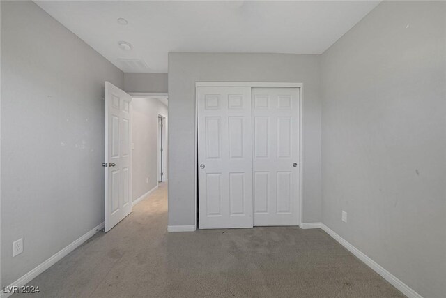 unfurnished bedroom featuring light carpet and a closet