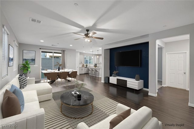 living room featuring dark wood-type flooring and ceiling fan