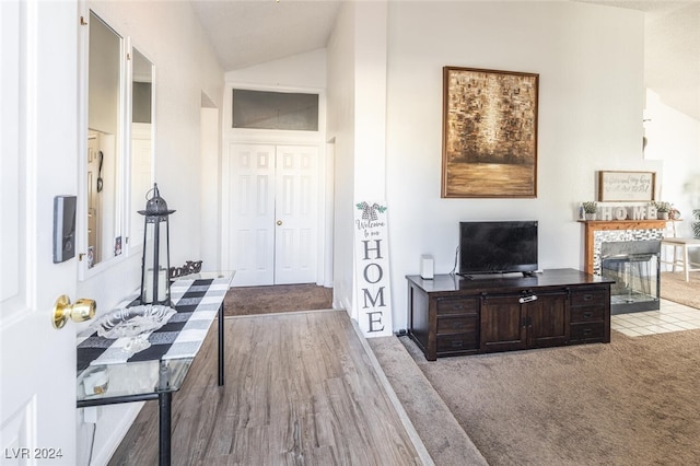 interior space with light hardwood / wood-style flooring, lofted ceiling, and a tiled fireplace