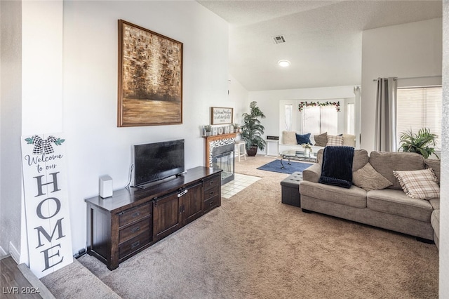 carpeted living room with lofted ceiling, a textured ceiling, and a tiled fireplace