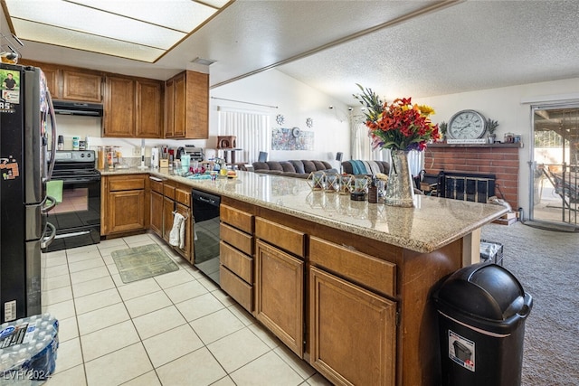 kitchen featuring black appliances, light colored carpet, kitchen peninsula, and a brick fireplace