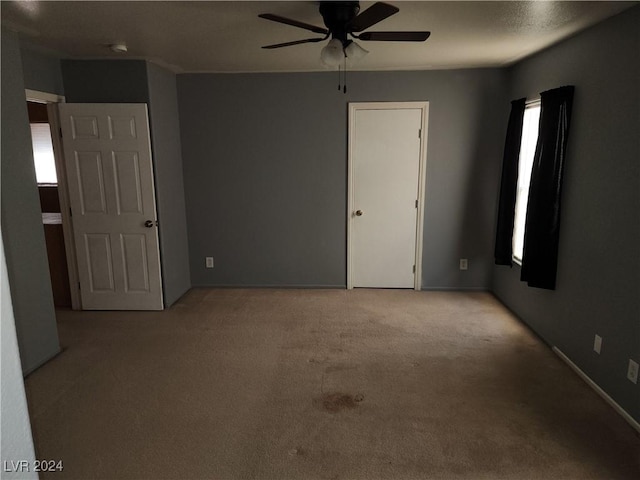 carpeted spare room featuring ceiling fan and a wealth of natural light