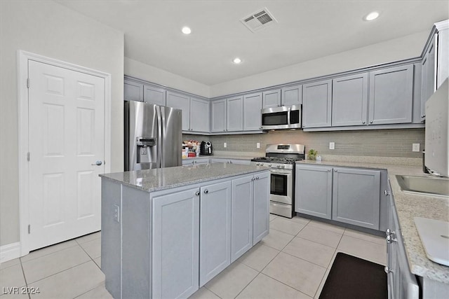 kitchen with decorative backsplash, appliances with stainless steel finishes, a center island, and gray cabinetry