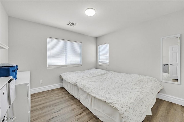 bedroom with multiple windows and light hardwood / wood-style flooring