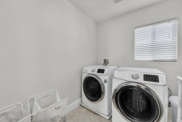 laundry room with independent washer and dryer and light tile patterned floors