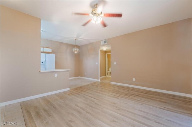 empty room with ceiling fan with notable chandelier and light wood-type flooring