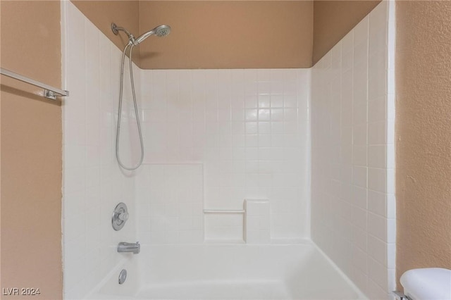 bathroom with tiled shower / bath combo and toilet