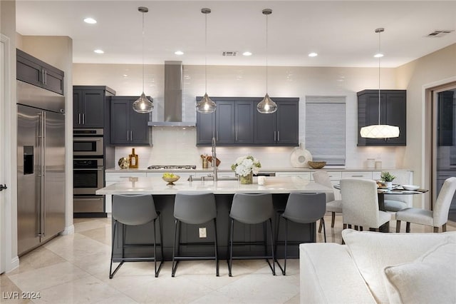 2781 Josephine Dr, Henderson, NV 89044 - kitchen featuring stainless steel appliances, wall chimney exhaust hood, a kitchen bar, backsplash, and pendant lighting
