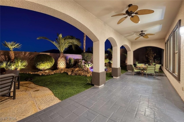 patio at twilight featuring ceiling fan