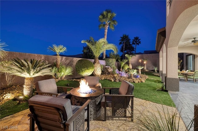 patio at twilight with a fire pit and ceiling fan