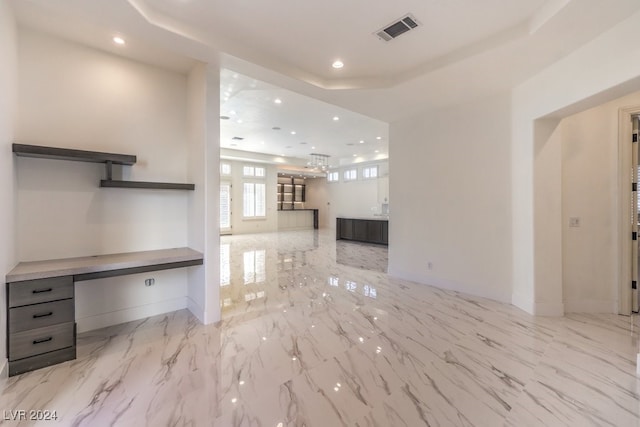 unfurnished living room featuring a raised ceiling and built in desk