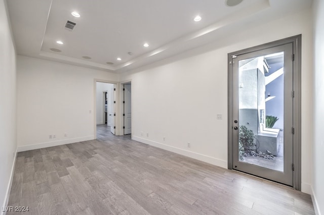 unfurnished room featuring a tray ceiling and light hardwood / wood-style flooring