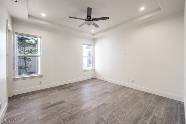 unfurnished room featuring a tray ceiling, ceiling fan, and hardwood / wood-style floors