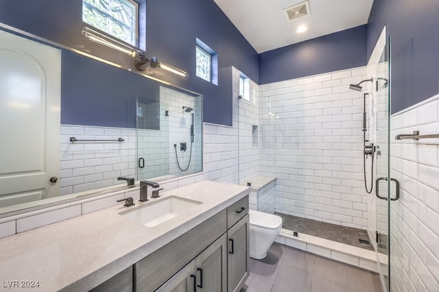 bathroom featuring vanity, a shower with door, tile patterned flooring, toilet, and tile walls