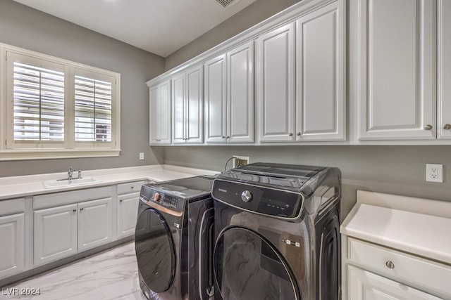 clothes washing area with washer and clothes dryer, cabinets, and sink