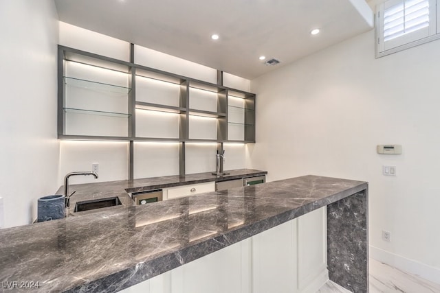 bar featuring sink and dark stone counters