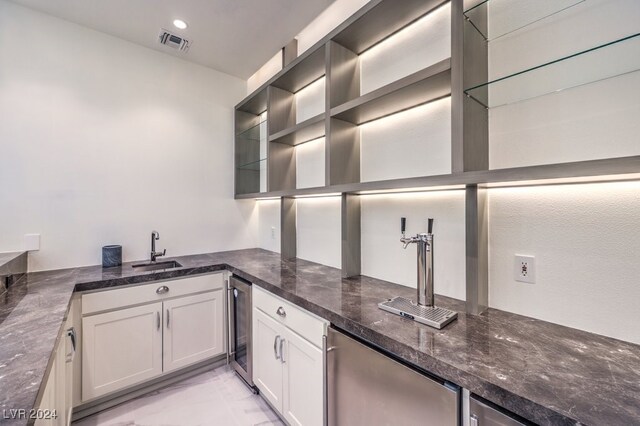 kitchen with stainless steel refrigerator, white cabinetry, wine cooler, and dark stone counters