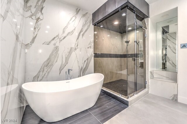 bathroom featuring shower with separate bathtub and tile walls