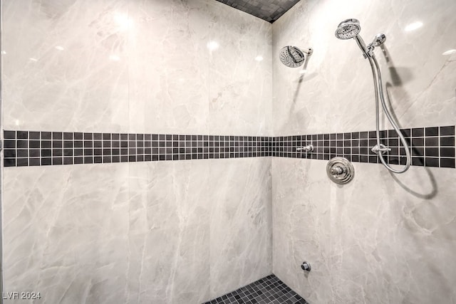 bathroom with a tile shower and tile walls