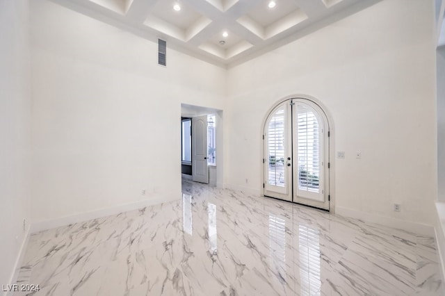 empty room featuring beam ceiling, french doors, a high ceiling, and coffered ceiling