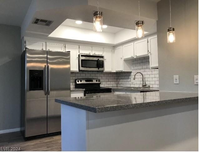 kitchen with white cabinetry, dark wood-type flooring, stainless steel appliances, backsplash, and kitchen peninsula