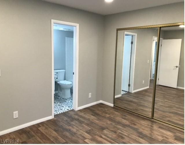 unfurnished bedroom featuring connected bathroom, a closet, and dark hardwood / wood-style flooring