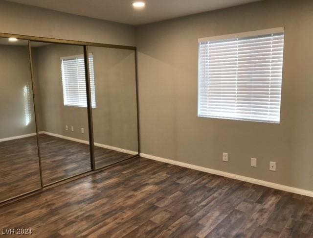 unfurnished bedroom featuring a closet and dark wood-type flooring