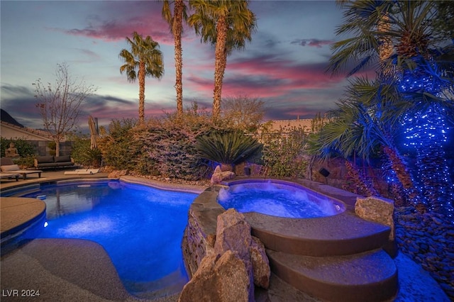 pool at dusk with an in ground hot tub