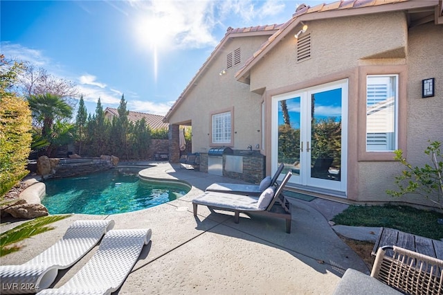 view of swimming pool featuring an outdoor kitchen, a patio area, and french doors