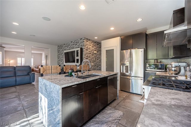 kitchen with appliances with stainless steel finishes, backsplash, dark brown cabinetry, a kitchen island with sink, and sink