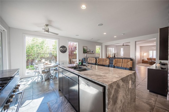 kitchen featuring ceiling fan, sink, stainless steel appliances, and an island with sink