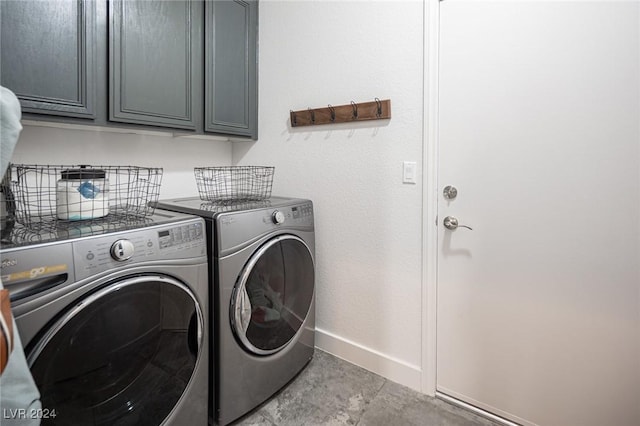 washroom featuring cabinets and washer and clothes dryer