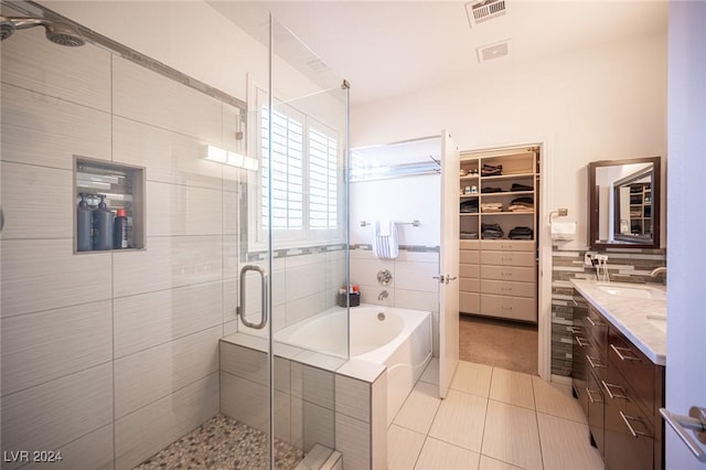 bathroom with tile patterned floors, vanity, independent shower and bath, and tile walls