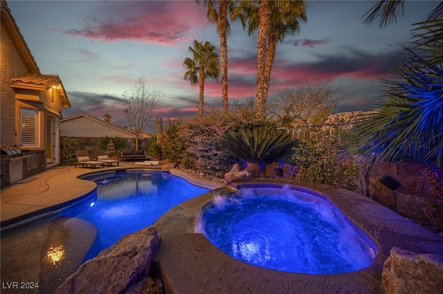 pool at dusk with an in ground hot tub and a patio