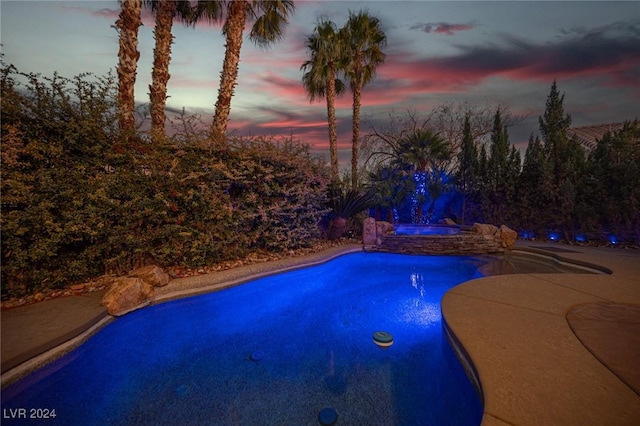 pool at dusk with an in ground hot tub