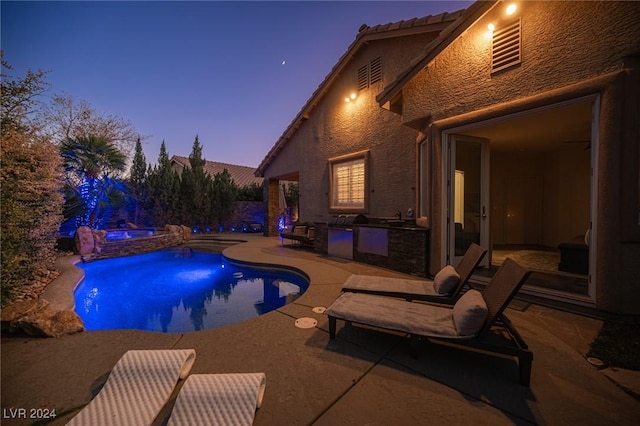 pool at dusk featuring an in ground hot tub, area for grilling, and a patio area