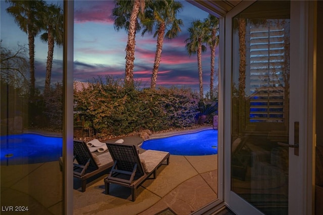 pool at dusk with a patio area