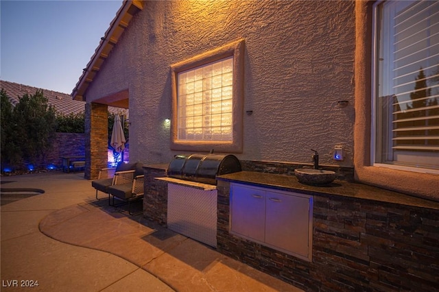 patio terrace at dusk featuring an outdoor kitchen