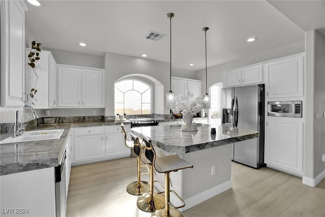 kitchen featuring white cabinets, a center island, light wood-type flooring, and stainless steel appliances