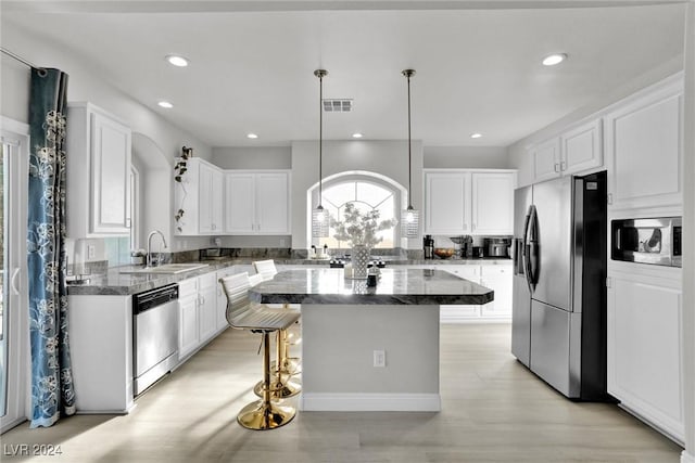 kitchen with appliances with stainless steel finishes, a center island, white cabinetry, and sink