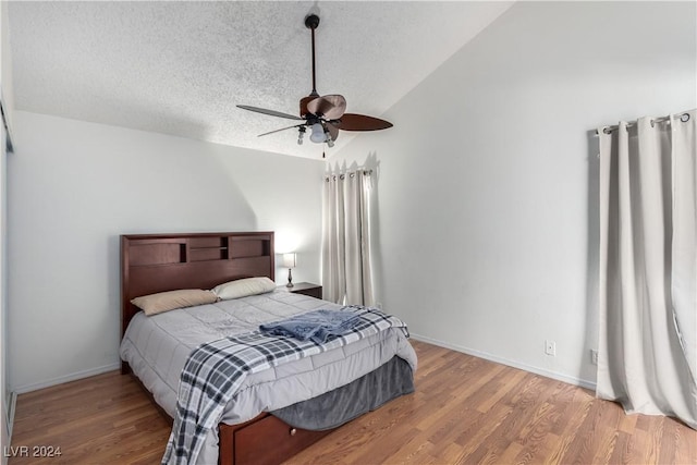 bedroom with hardwood / wood-style floors, ceiling fan, lofted ceiling, and a textured ceiling