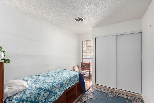 bedroom with hardwood / wood-style floors, a textured ceiling, and a closet