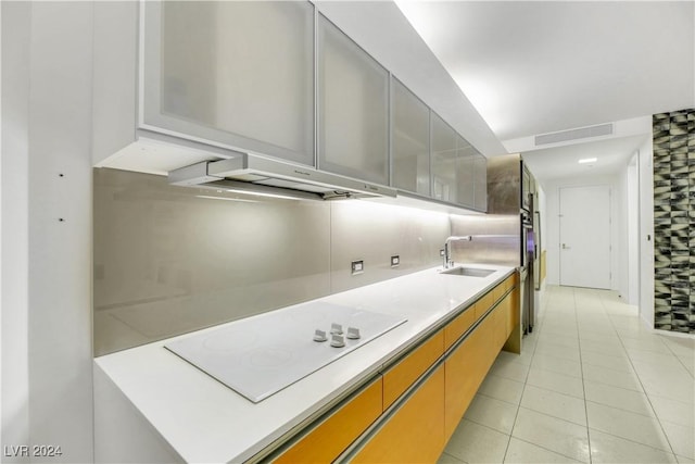 kitchen with decorative backsplash, white electric cooktop, light tile patterned floors, and sink