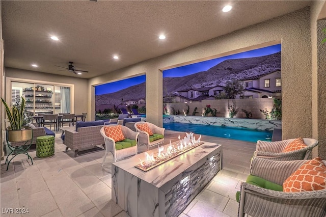 view of patio featuring a mountain view, an outdoor living space with a fire pit, and ceiling fan