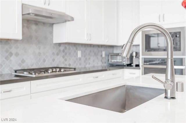 kitchen with stainless steel gas stovetop, white cabinetry, and tasteful backsplash