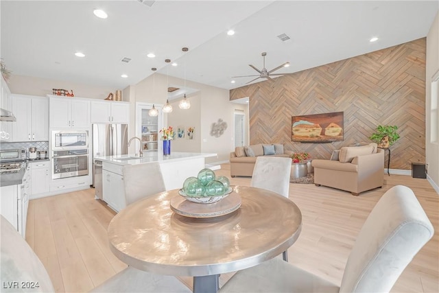 dining space with ceiling fan, sink, and light wood-type flooring